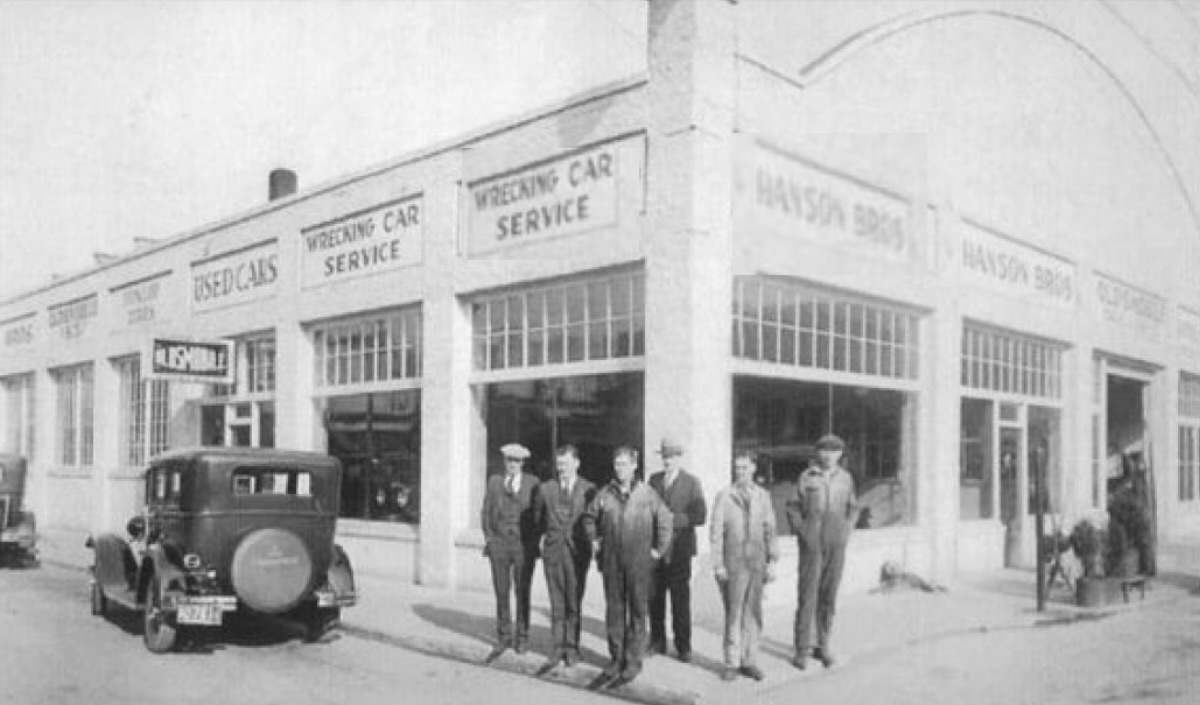 image of the Braveside building from its early days - black and white - 6 men standing on the corner outside with an old style car visible